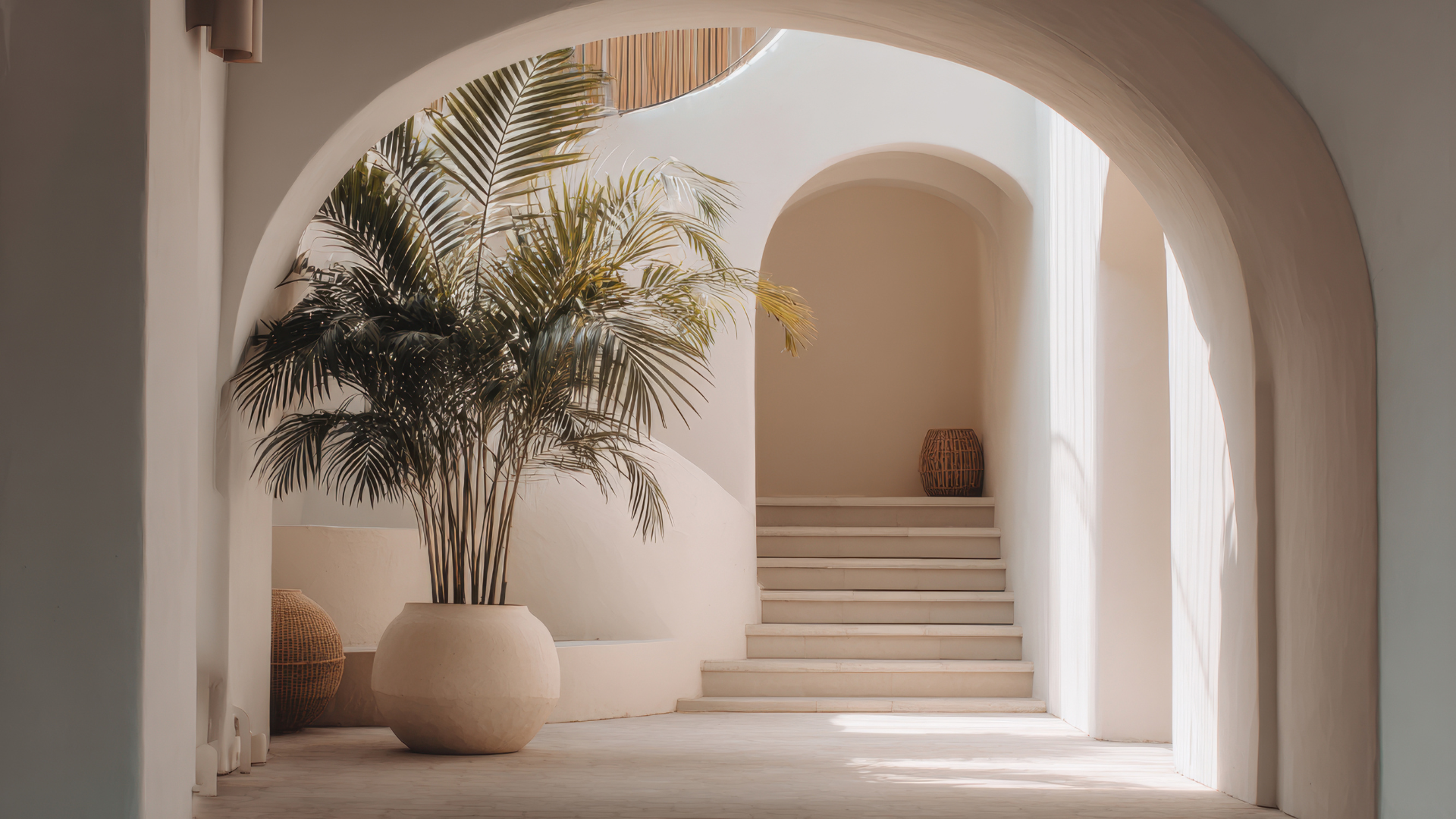 An inviting archway opens to a graceful staircase, framed by a lush potted plant in the foreground, infusing this professional office space with a breath of natural calm.