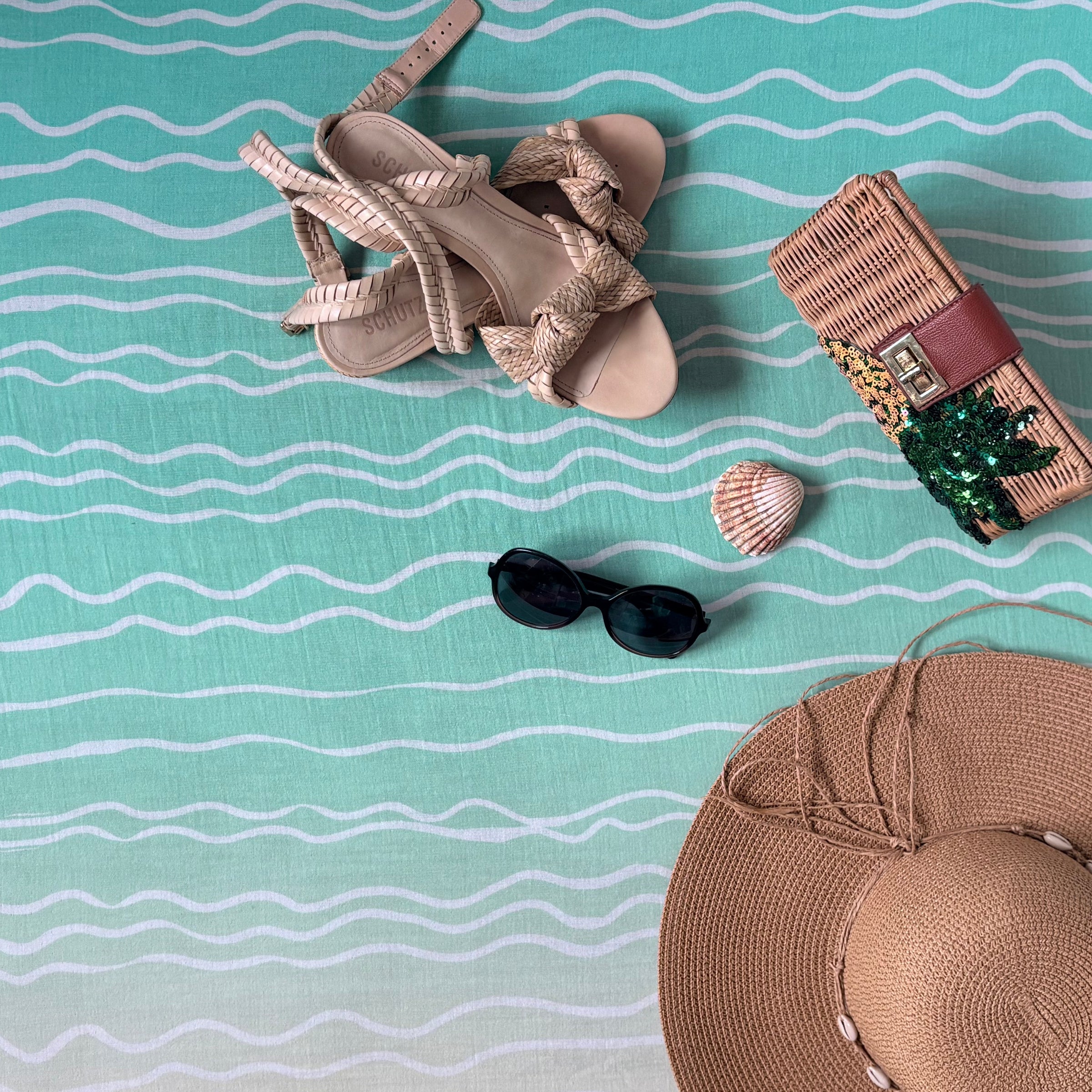 Beige sandals, sunglasses, shell, and straw hat on the large square blanket in Brisa do Mar design