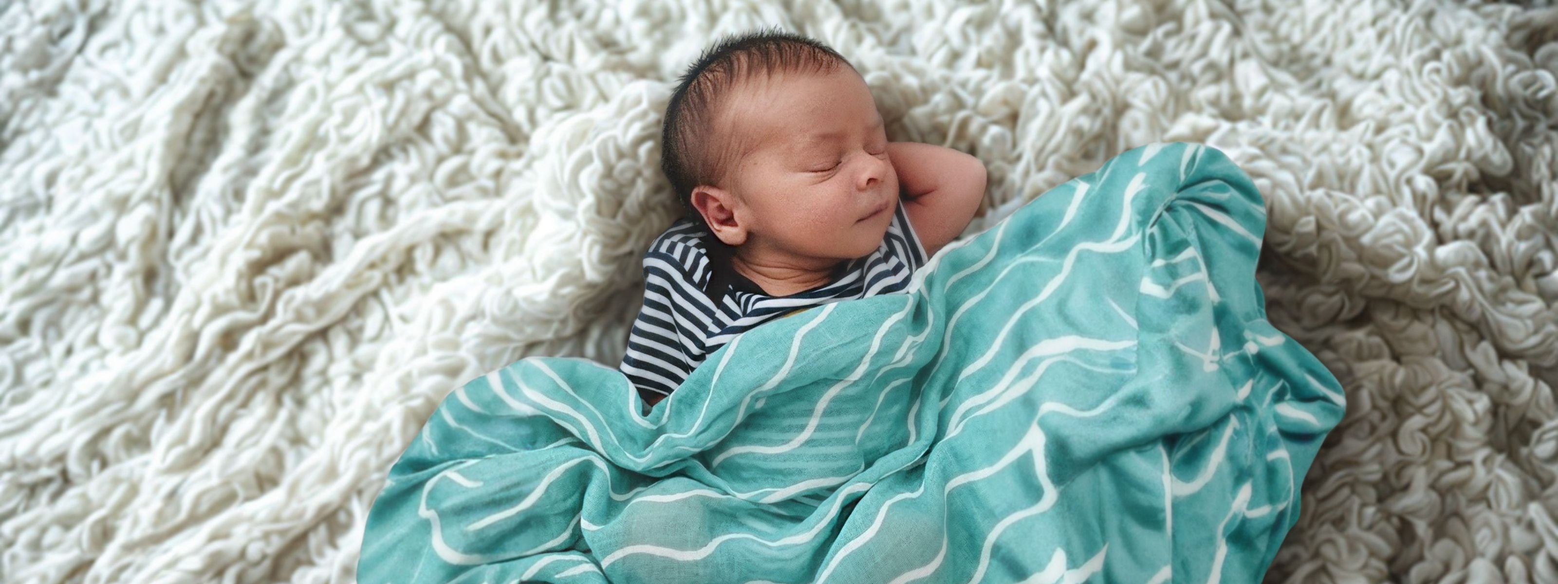 Baby wrapped in the Brisa do Mar Little Battersea muslin at home, a calm and considered essential for early family moments.