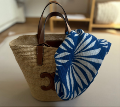 Close-up of a woven bag with an Azul Tropique organic muslin bandana, symbolizing Little Battersea's elegant design and product versatility.