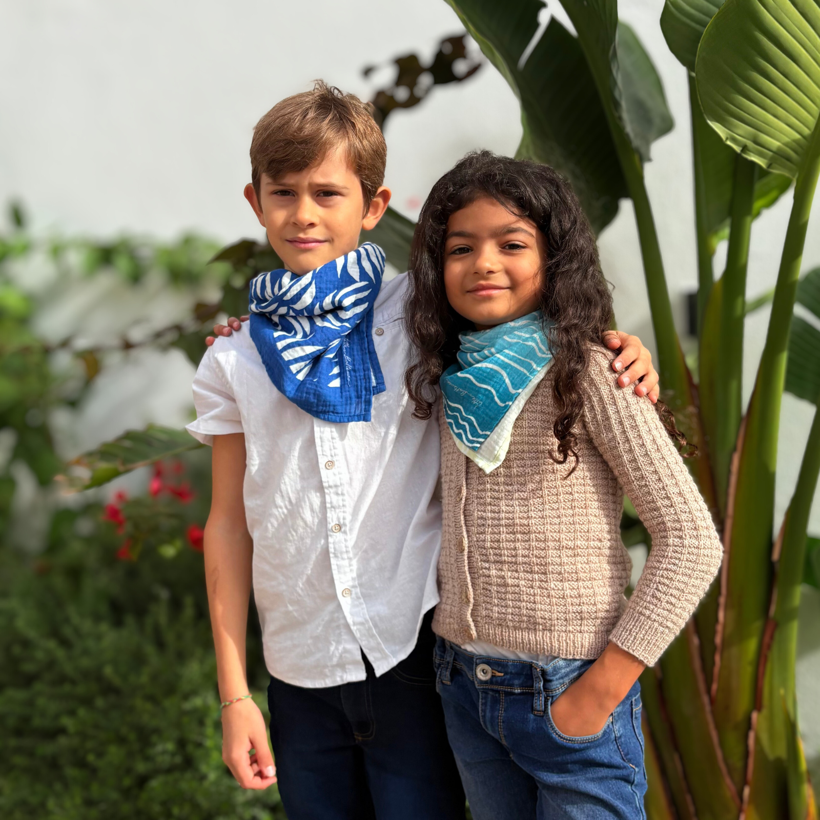 Two organic muslin bandanas in Azul Tropique and Brisa do Mar designs by Little Battersea, perfect for babies, children, adults as stylish accessories.