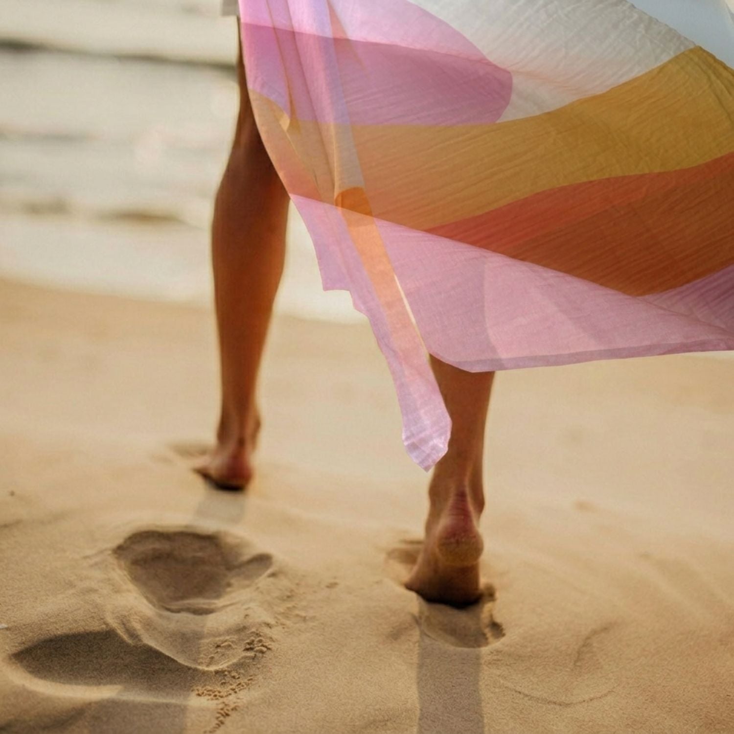 Woman walking on a beach with a Golden Indra Large Square colorful Sarong.
