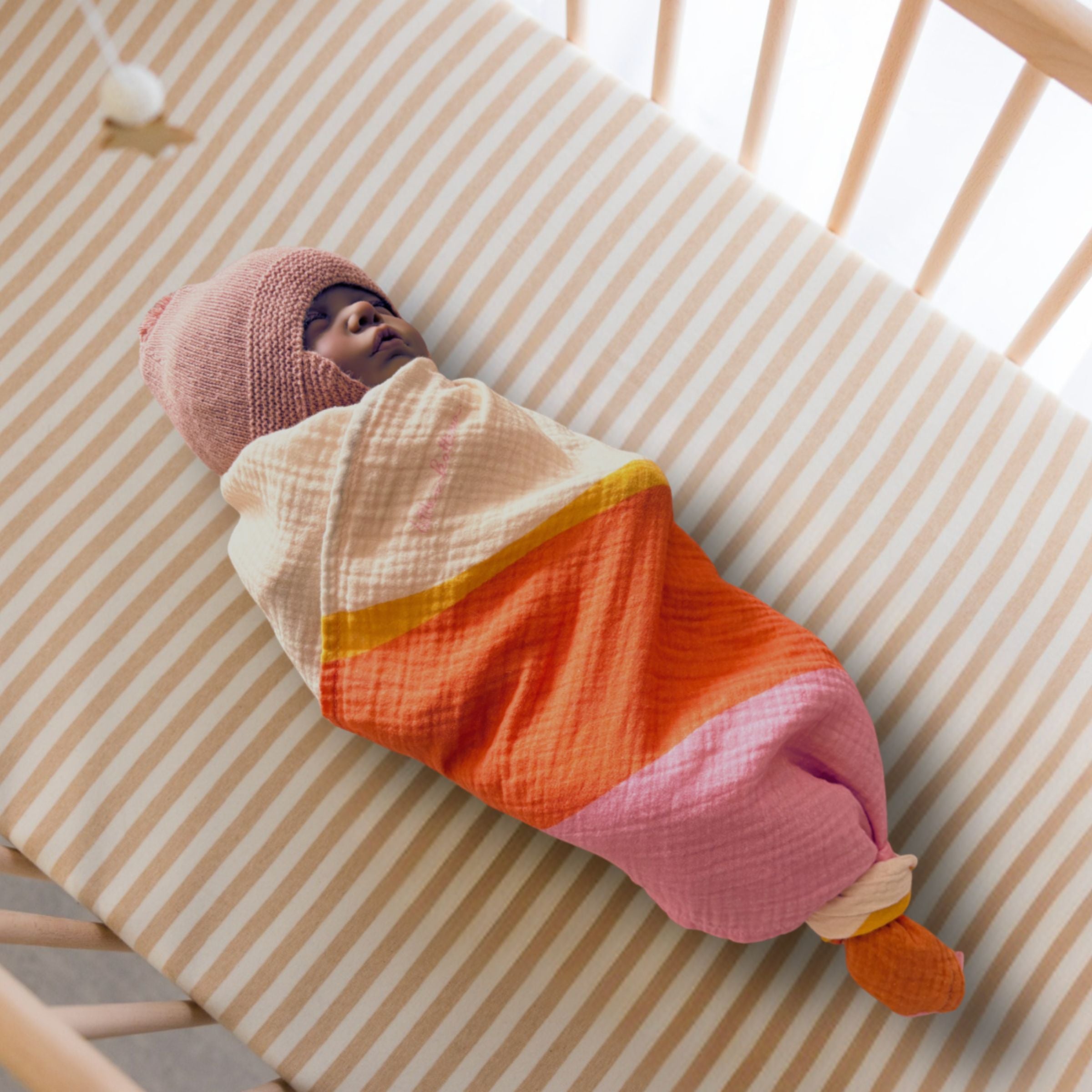 Newborn asleep, fully swaddled in crib with Golden Indra