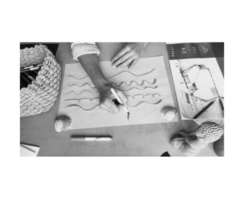 A creative mind at work: hands sketching inspired designs amid an array of tools on a sunlit table, blending imagination with precision.